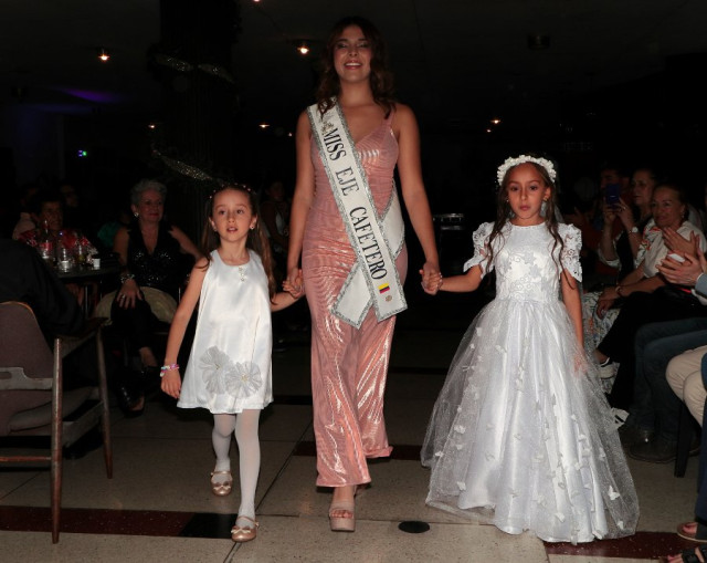 Miss Eje Cafetero, Sofía Arenas, desfila en Salamina acompañada de dos niñas.