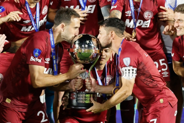 Carlos Izquierdoz (i) y Lautaro Acosta de Lanús celebran con el trofeo