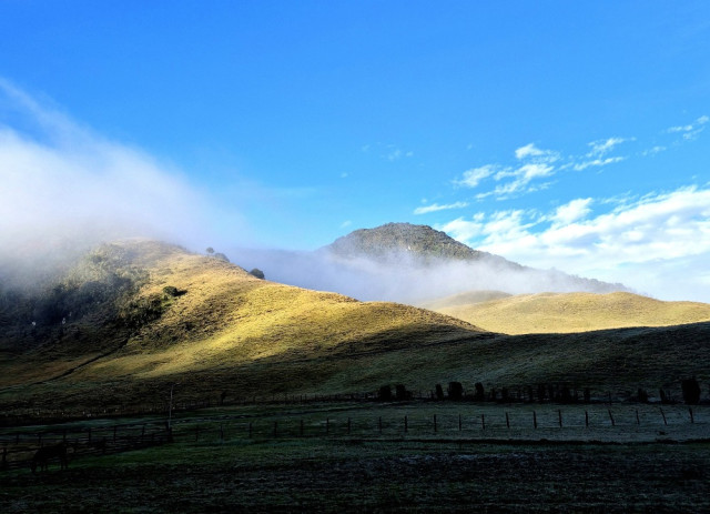 El azul intenso del cielo contrastó con el verde de la montaña y el blanco de las nubes.