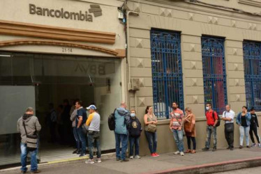Gente hace fila afuera de una oficina de Bancolombia en el centro de Manizales.