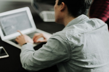 Hombre consulta algo en un computador portatil.