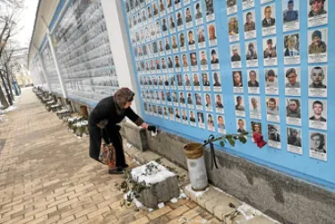 Una señora limpia las lozas de un mural de homenaje a los soldados y milicianos ucranianos caídos desde la invasión de Rusia en el 2014, en el Monasterio de San Miguel de las Cúpulas Doradas en Kyiv.