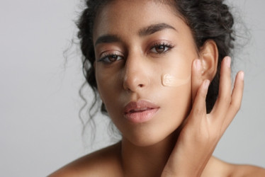 Mujer aplicándose protector solar en la cara.