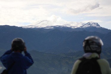 Dos motociclistas se estacionaron por el barrio Centenario de Manizales para registrar con sus celulares una imagen del volcán Nevado del Ruiz.