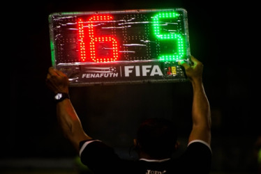Árbitro de fútbol muestra un aviso de sustitución en un partido.
