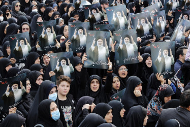 Mujeres iraníes vestidas con chadores negros sostienen carteles del difunto presidente iraní Ebrahim Raisí mientras participan en una ceremonia de luto en Teherán este lunes.