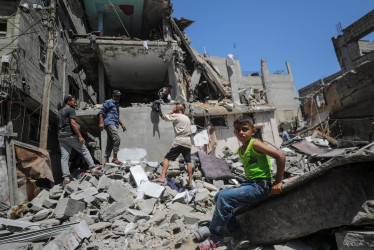 Un niño observa la búsqueda de personas desaparecidas bajo los escombros de una casa destruida tras un ataque aéreo israelí en el campo de refugiados de al-Nuseirat