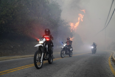 Policías patrullan la zona cercana donde se registra el incendio forestal en Quito (Ecuador).