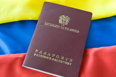 Pasaporte colombiano con una bandera colombiana detrás