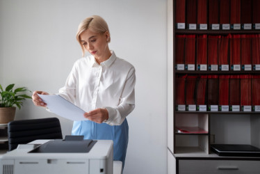 Mujer usando impresora mientras trabaja en la oficina.