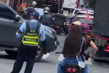 Esta es la imagen que circula en redes sociales, en donde se observa a la parrillera sin el casco y el agente de tránsito regulando el tráfico a un metro de distancia.