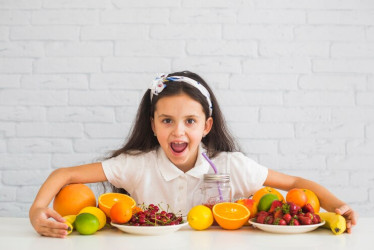 Niña sostiene frutas y verduras. Los expertos recomiendan una buena alimentación. 