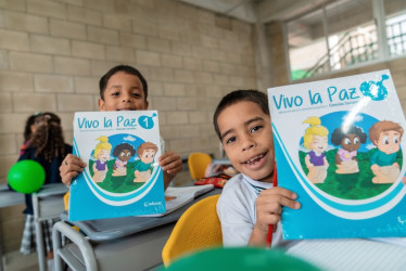 Dos niños sostienen una cartilla escolar sobre la paz. 