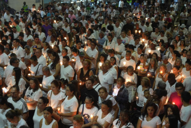 Personas vestidas de blanco sostienen velas encendidas en una 'velatón' por la paz y la memoria este domingo, frente a la Base Aérea Marco Fidel Suárez, en Cali. 