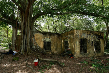 Foto del 5 de noviembre del 2025 que muestra personas sentadas cerca a una casa en ruinas, en Armero.