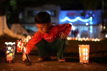Un niño enciende velas durante la tradicional Noche de las Velitas este domingo, en Cali (Colombia). 