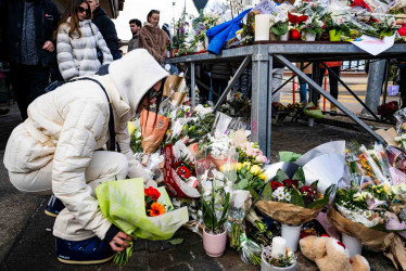 Una mujer deposita flores cerca del lugar donde se produjo un incendio de origen desconocido en el bar y salón «Le Constellation», que dejó varios muertos y heridos durante la celebración de Año Nuevo