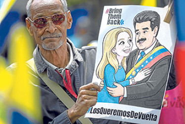 Un hombre sostiene un cartel con la imagen del derrocado líder de Venezuela Nicolás Maduro junto a su esposa, Cilia Flores, como reacción durante la segunda audiencia de Maduro y Flores desarrollada en Nueva York, pidiendo justicia y la liberación para la pareja.