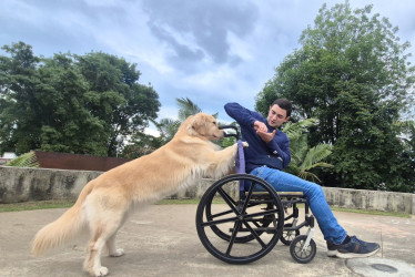 Mandarina, una golden retriever en formación, empuja una silla de ruedas bajo las indicaciones de Juan Sebastián Montoya, entrenador canino, quien lidera un proyecto para formar perros de asistencia que mejoren la calidad de vida de personas en condición de discapacidad.