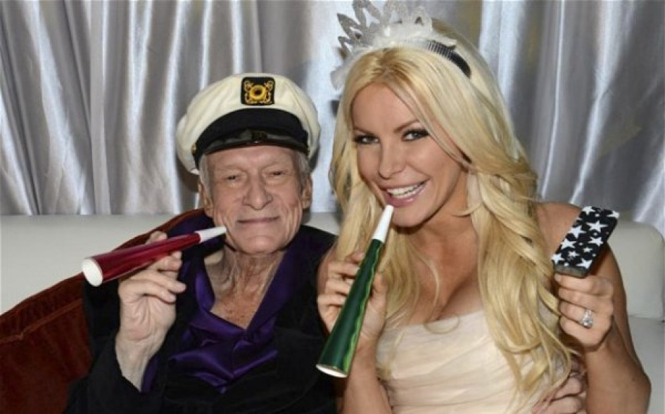 Hugh Hefner con una conejita Playboy sentados en un sofá