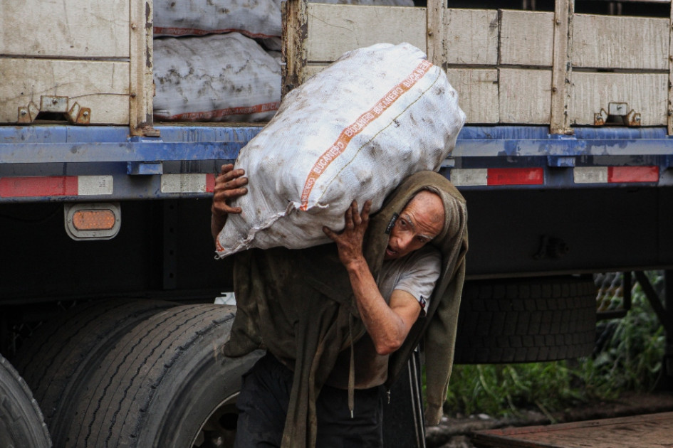 Nelson Javier Sánchez sale en bicicleta a la 1:30 a.m. desde su casa en el barrio la Toscana y se dirige hasta su lugar de trabajo en la Plaza de Mercado. Allí labora todo el día. Ser cotero ha sido su oficio de toda la vida. En la foto se le ve descargando un bulto de papa de 50 kilogramos.