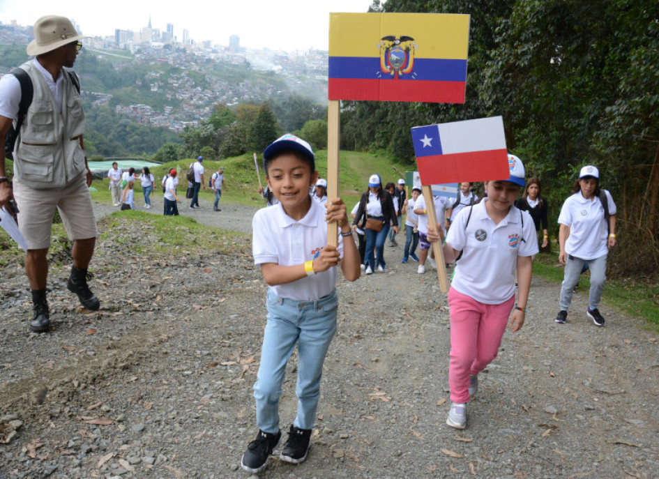 Joselin Abigaíl Tuquinga, de Ecuador; era seguida por Francisca Ignacia González, de Chile; mientras recorrían los terrenos del Parque Tecnológico Ambiental La Esmeralda. Ellas y seis niños más resultaron ganadores de la 10a edición de la campaña Alrededor de Iberoamérica, con la que se pretende educar en el cuidado del medioambiente.