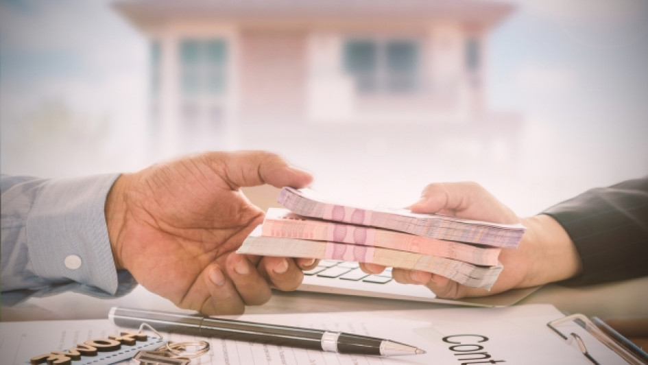 Mano pasando un fajo de billetes a otra mano.