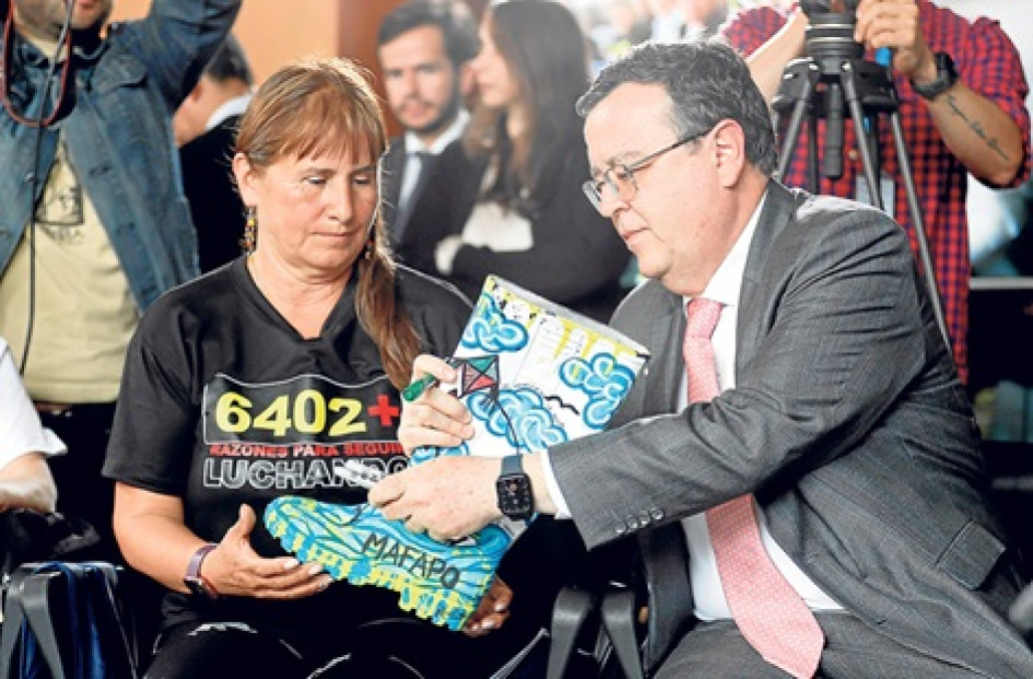 Foto | EFE | LA PATRIA El presidente de la Jurisdicción Especial para la Paz (JEP), Alejandro Ramelli, entrega una bota intervenida artísticamente a Jackeline Castillo, presidenta de Mafapo, que simboliza el dolor de las ejecuciones extrajudiciales.