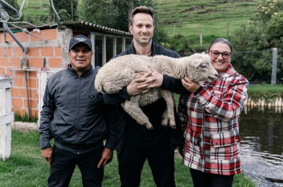 Gary el Gringo sostiene una oveja, mientras posa con lugareños de Marulanda (Caldas).