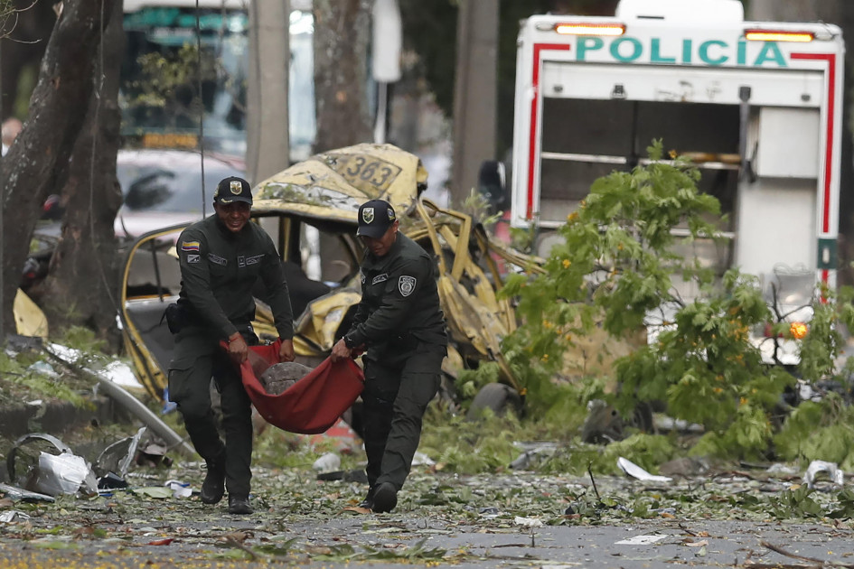 Integrantes de la Policía Nacional trasladan un cilindro tras una explosión en inmediaciones de la Escuela Militar de Aviación Marco Fidel Suárez este jueves, en Cali (Colombia). Al menos cinco personas murieron y 36 resultaron heridas por un atentado perpetrado con un camión bomba.