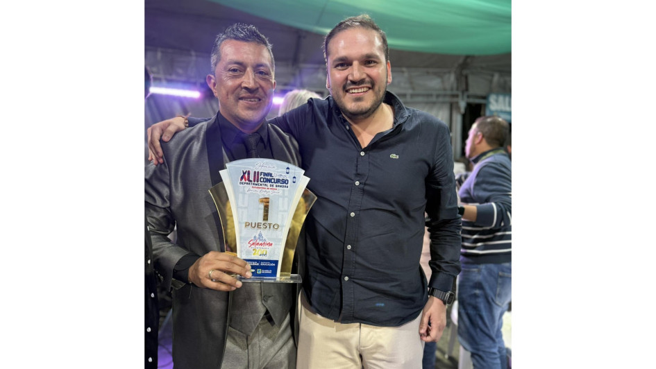 El alcalde de Neira, Jhon Jairo Castaño, posa con el director de la banda del municipio, Holver Mauricio Cardona, con el galardón que acredita a la agrupación como la ganadora del Concurso Departamental de Bandas este 2025 en Caldas.