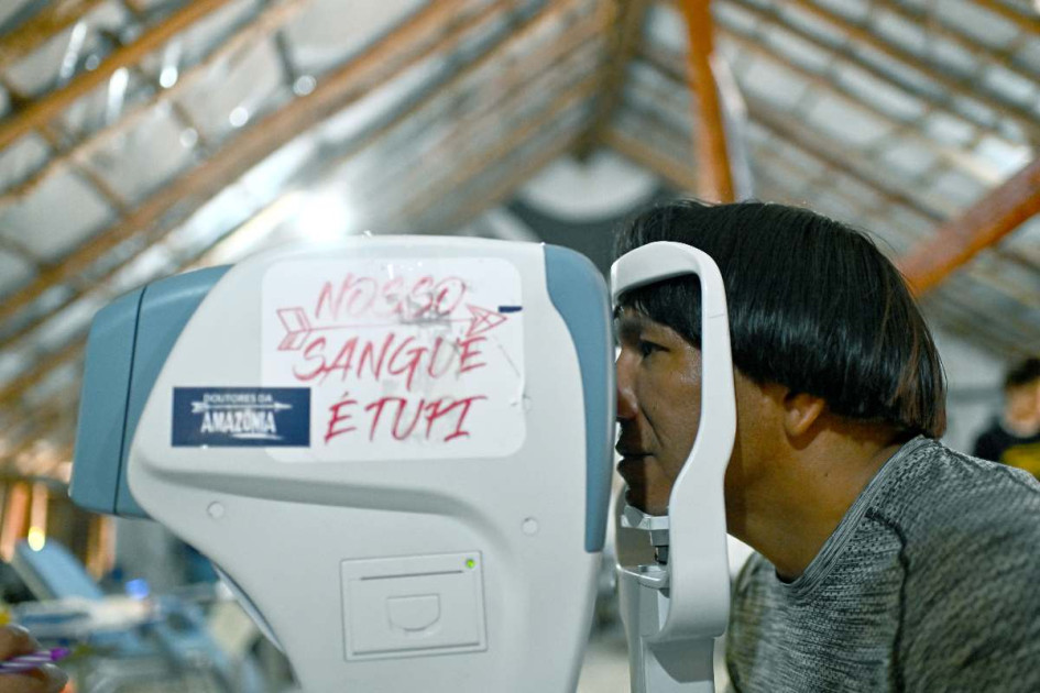 El jefe indígena Akauã Kamayurá hace una prueba visual en un equipo médico, con las letras que dicen en portugues 'Nuestra sangre es Tupi'. 