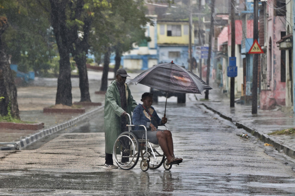 Personas se protegen de la lluvia este martes, en Santiago de Cuba (Cuba).