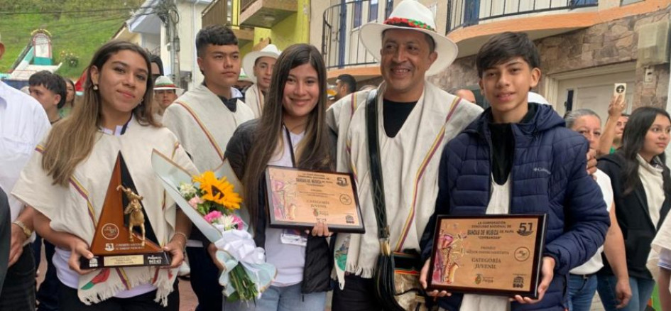El director de la banda sinfónica estudiantil del Instituto Neira, Holver Mauricio Cardona, en compañía de algunos músicos quienes exhiben los reconocimientos obtenidos en Paipa (Boyacá). 