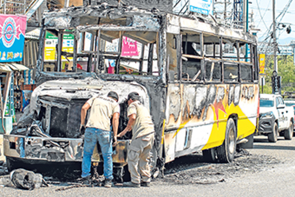 FotoA | EFE | LA PATRIA  Trabajadores de una grúa enganchan un autobús quemado por presuntos integrantes del crimen organizado ayer en el balneario de Acapulco (México).